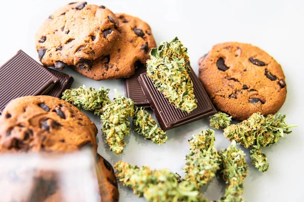 Biscotti con erba di cannabis CBD. Biscotti con cannabis e germogli di marijuana sul tavolo. Trattamento della marijuana medica per uso alimentare, sfondo bianco . — Foto Stock