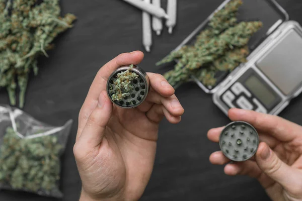 Een man een grinder gebruikt marihuana fijn te maken — Stockfoto