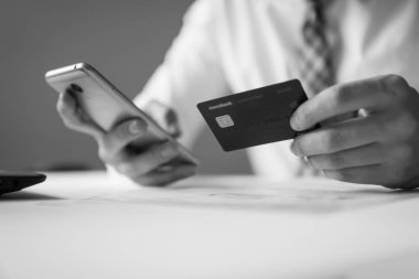 Malların online ödeme. Online Döviz Alım Satım ticaret. Akıllı telefon ve Internet ticareti. Online ödeme telefon aracılığıyla. Onun elinde banka kredi kartıyla genç işadamı.