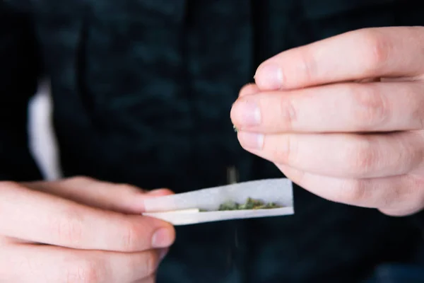 Närbild av missbrukare belysning upp marijuana joint med ljusare. Narkotika missbruk. Man rullande en marijuana joint. Man förbereder och rullande marijuana cannabis joint. Droger narkotiska begrepp. Närbild . — Stockfoto