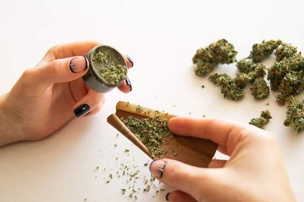 Vrouw voorbereiding en Rolling marihuana cannabis joint. Cannabis gebruik concept. Close-up van marihuana bot met Grinder. Vrouw die een marihuana rolt stomp op witte achtergrond. — Stockfoto