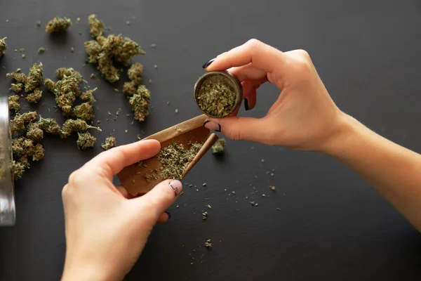 Woman preparing and rolling marijuana cannabis joint. Close up of marijuana blunt with grinder. Marijuana use concept. Woman rolling a marijuana joint. — Stock Photo, Image