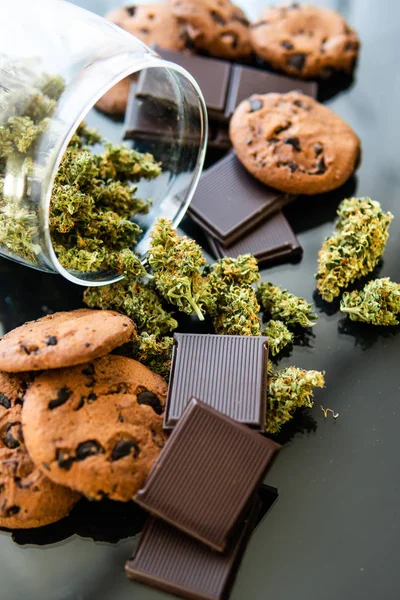 Cookies with cannabis and buds of marijuana on the table. Cookies with cannabis herb CBD. Treatment of medical marijuana for use in food, black background. — Stock Photo, Image