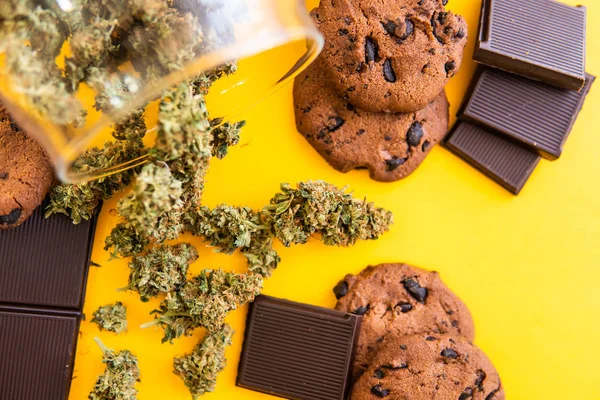 Cannabis CBD herb Cookies. Galletas con cannabis y cogollos de marihuana sobre la mesa. Tratamiento de la marihuana medicinal para uso en alimentos, fondo amarillo . — Foto de Stock