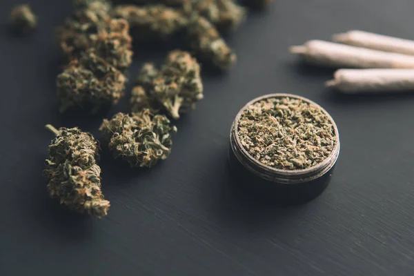 Porro con hierba, molinillo con marihuana fresca, vista superior, brotes de cannabis en la mesa negra, de cerca , — Foto de Stock