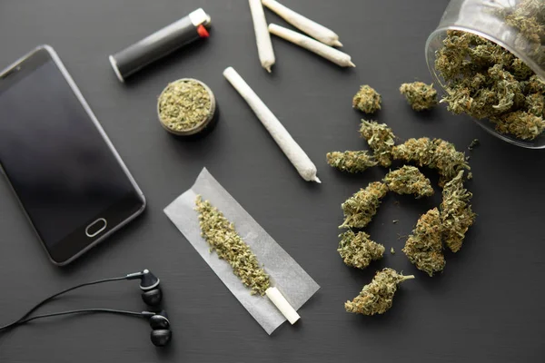 Porro con hierba, brotes de cannabis en la mesa negra, de cerca, molinillo en la mano con marihuana fresca , —  Fotos de Stock
