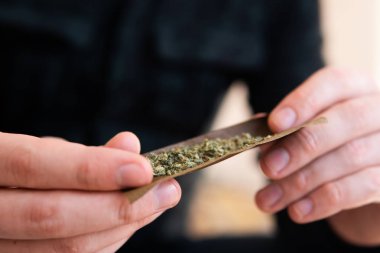 Marihuana Blunt 'ı çakmakla yakmaya çalış. Kapatın. Uyuşturucu narkotik konsepti. Marihuana kullanan bir adam. Esrar hazırlayan ve yuvarlayan adam Blunt..