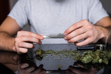 Esrar saran bir adam. Uyuşturucu kullanımı. Kapatın. Marihuana hazırlayan ve yuvarlayan adam. Esrarkeşin çakmakla esrar içtiği yeri kapatın. Uyuşturucu uyuşturucu konsepti.