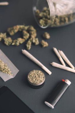 Esrarlı esrar, elinde öğütücü elinde taze marihuana, siyah masada esrar tomurcukları, yakın çekim, dikey çekim