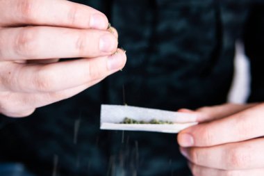 Esrarkeşin çakmakla esrar içtiği yeri kapatın. Kapatın. Uyuşturucu kullanımı. Esrar saran bir adam. Marihuana hazırlayan ve yuvarlayan adam. Uyuşturucu uyuşturucu konsepti.