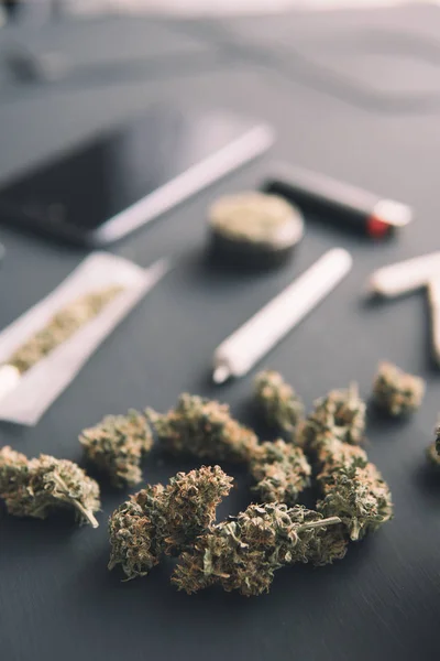 Molen in de hand met verse Cannabis, close up, marihuana knoppen op zwarte tafel, joint met weed, verticaal schot — Stockfoto