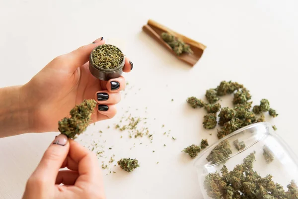 Femme roulant un cannabis contondant sur fond blanc. Gros plan de marijuana émoussée avec broyeur. concept de consommation de marijuana. Femme préparant et roulant marijuana cannabis joint . — Photo