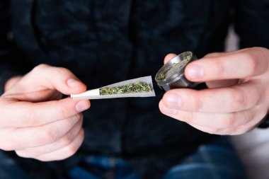 Marihuana hazırlayan ve yuvarlayan adam. Esrar saran bir adam. Uyuşturucu narkotik konsepti. Esrarkeşin çakmakla esrar içtiği yeri kapatın. Kapatın. Uyuşturucu kullanımı.