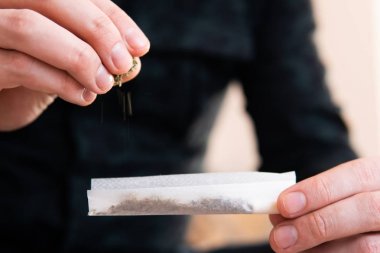Uyuşturucu narkotik konsepti. Uyuşturucu kullanımı. Kapatın. Esrar saran bir adam. Marihuana hazırlayan ve yuvarlayan adam. Marihuanayı çakmakla yakan bağımlıya yakın..