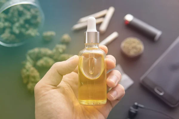 Handheld fles Cannabis olie in pipet, natuurlijk kruid, CBD cannabis olie. close-up, hennepproduct, medicinale marihuana concept, lichte lekken kleurtonen — Stockfoto