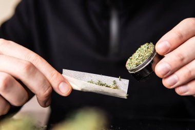 Çakmakla marihuana dükkanını kapat. Esrar saran bir adam. Esrar saran bir adam..