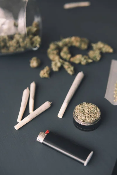 Molinillo en la mano con marihuana fresca, brotes de cannabis en la mesa negra, de cerca, articulación con hierba, tiro vertical —  Fotos de Stock