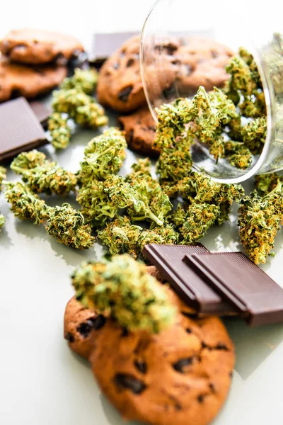 Bolachas com erva de cannabis CBD. Tratamento de maconha medicinal para uso em alimentos, fundo branco. Biscoitos com maconha e botões de maconha na mesa. Tiro vertical — Fotografia de Stock