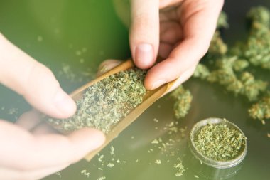 Bağımlının marihuana esrarını çakmakla aydınlatması yakın. Adam hazırlanıyor ve esrar esrar ortak haddeleme. Marihuana küntbir adam. Pot kullanım konsepti. Yakından kapatın. ışık yalar renk tonlu