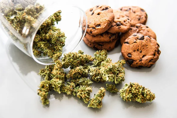 Galletas con cannabis y cogollos de marihuana sobre la mesa. Galletas con hierba de cannabis CBD. Tratamiento de la marihuana medicinal para uso en alimentos, fondo blanco . —  Fotos de Stock