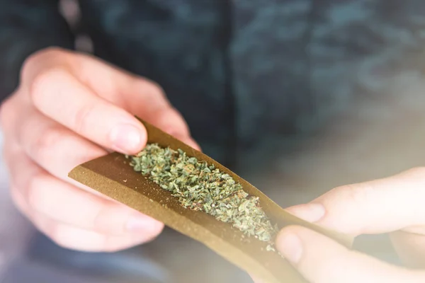 Hombre preparando y rodando marihuana cannabis Blunt. De cerca. Primer plano de adicto encendiendo marihuana Blunt con encendedor. Concepto de drogas narcóticas. Hombre rodando una marihuana Blunt Consumo de drogas . —  Fotos de Stock