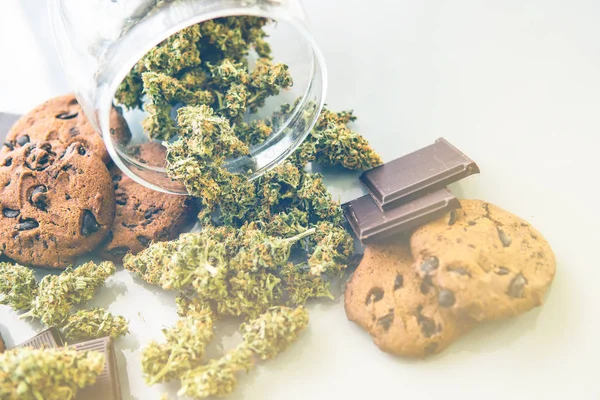 Kannabiszos sütik és marihuána rügyek az asztalon. Kannabiszos sütik CBD-vel. Orvosi marihuána kezelése élelmiszerekben, fehér háttér. fényszivárgás — Stock Fotó