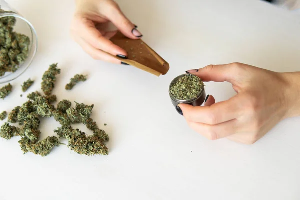 Cierre de marihuana roma con molinillo. Mujer rodando un porro de marihuana sobre fondo blanco. Concepto de consumo de marihuana. Mujer preparando y rodando marihuana marihuana conjunta . —  Fotos de Stock