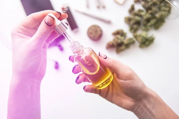 Olie Cannabis CBD in pipet vrouwen hand, marihuana extract op witte achtergrond, medisch hennep concept, onkruid product, close-up, lichte lekken kleurtonen — Stockfoto