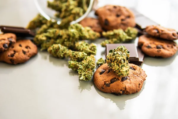 Cookies with cannabis and buds of marijuana on the table. Treatment of medical marijuana for use in food, white background. Cookies with cannabis herb CBD. — Stock Photo, Image