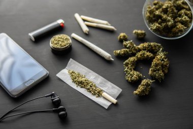 Esrarlı esrar, siyah masada marihuana tomurcukları, yakın plan, elinde taze esrarla öğütücü,