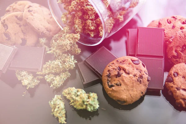 Шоколад и печенье с марихуаной на столе. Лечение медицинской марихуаны для использования в пищу, черный фон. Концепция печенья и шоколада с травой каннабиса CBD . — стоковое фото