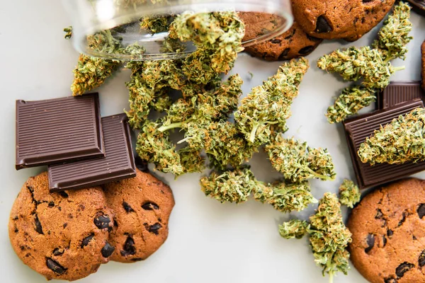 Biscotti con erba di cannabis CBD. Biscotti con cannabis e germogli di marijuana sul tavolo. Trattamento della marijuana medica per uso alimentare, sfondo bianco . — Foto Stock