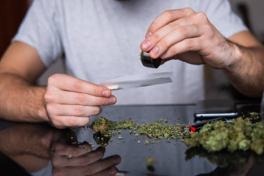 Esrarkeşin çakmakla esrar içtiği yeri kapatın. Uyuşturucu narkotik konsepti. Kapatın. Esrar saran bir adam. Uyuşturucu kullanımı. Marihuana hazırlayan ve yuvarlayan adam.