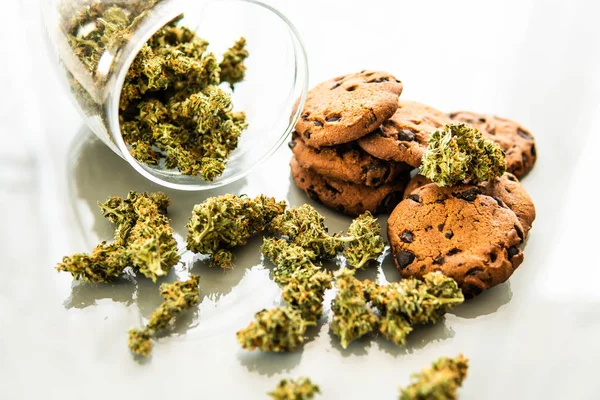 Biscoitos com maconha e botões de maconha na mesa. Bolachas com erva de cannabis CBD. Tratamento de maconha medicinal para uso em alimentos, fundo branco . — Fotografia de Stock