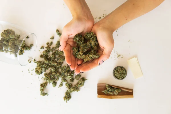 Feche a maconha na mão. Conceito de uso de maconha. Mulher e cannabista no fundo branco da mão. Mulher preparando cannabis maconha. Vista superior — Fotografia de Stock