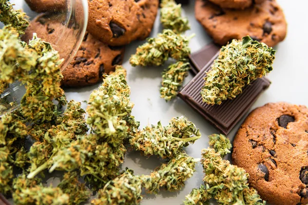 Galletas con hierba de cannabis CBD. Galletas con cannabis y cogollos de marihuana sobre la mesa. Tratamiento de la marihuana medicinal para uso en alimentos, fondo blanco . —  Fotos de Stock