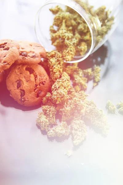 Kekse mit Cannabis und Knospen Marihuana auf dem Tisch. Behandlung von medizinischem Marihuana zum Verzehr in Lebensmitteln, schwarzer Hintergrund. Konzept des Kochens mit Cannabiskraut. Leck bei vertikalem Schusslicht — Stockfoto