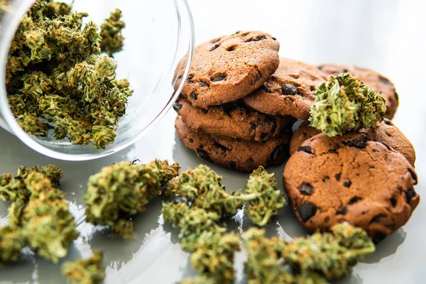 Koekjes met cannabis kruid CBD. Behandeling van medicinale marihuana voor gebruik in voedsel, witte achtergrond. Koekjes met cannabis en knoppen marihuana op tafel. — Stockfoto