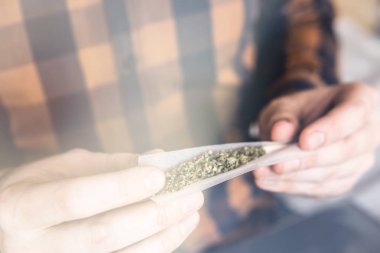 Marihuana hazırlayan ve yuvarlayan adam. Esrarkeşin çakmakla esrar içtiği yeri kapatın. Uyuşturucu narkotik konsepti. Esrar saran bir adam. Uyuşturucu kullanımı. Kapat. .