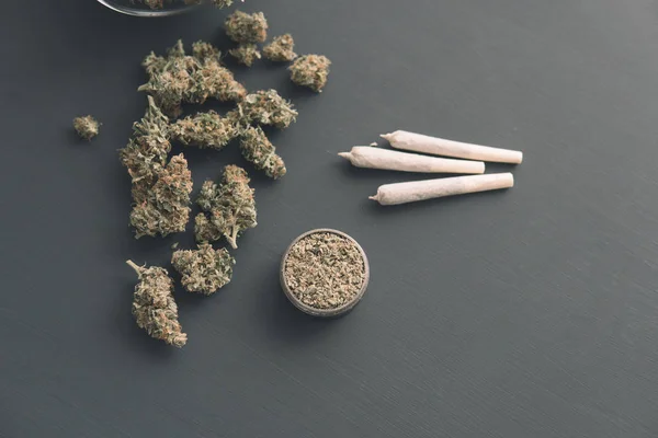Porro con hierba, brotes de cannabis en la mesa negra, vista superior, molinillo con marihuana fresca , — Foto de Stock