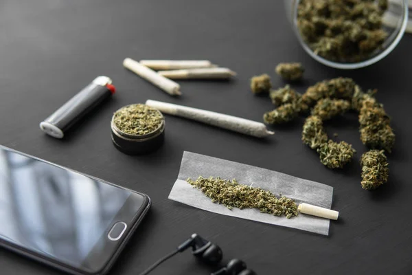 Kvarn i hand med färska Cannabis, joint med gräs, marijuana knoppar på svart bord, närbild, — Stockfoto