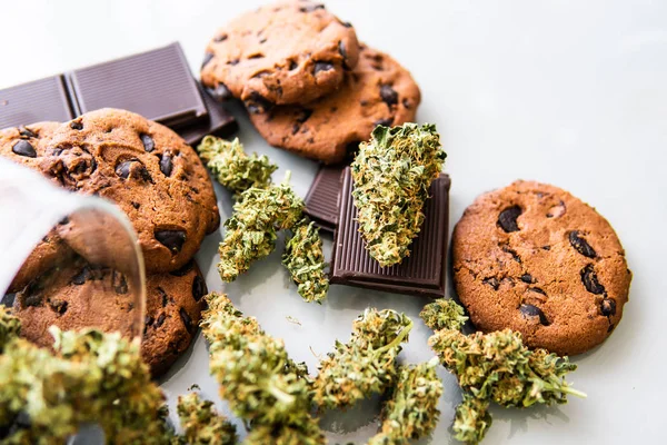 Koekjes met cannabis en knoppen marihuana op tafel. Behandeling van medicinale marihuana voor gebruik in voedsel, witte achtergrond.Cookies met cannabiskruid CBD. — Stockfoto