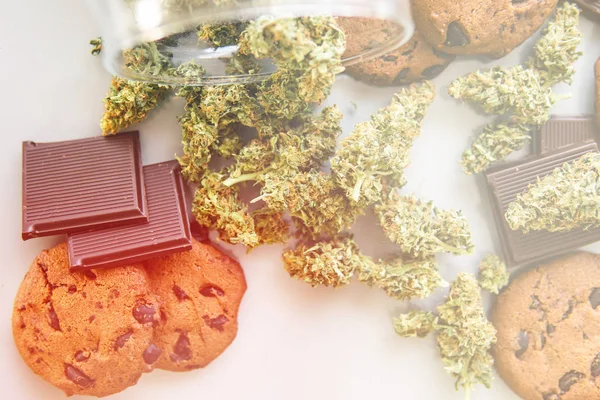 Galletas con hierba de cannabis CBD. Tratamiento de la marihuana medicinal para uso en alimentos, fondo blanco. Galletas con cannabis y cogollos de marihuana sobre la mesa. fugas ligeras — Foto de Stock