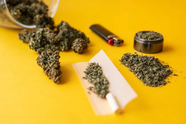 Stumpf und Feuerzeuge. Hanf-Legalisierung. Kräutermühle Frische Marihuana. CBD und THC auf Knospen in Cannabis. Ansicht von oben. Cannabis-Knospen in der Hand auf gelbem Hintergrund. — Stockfoto