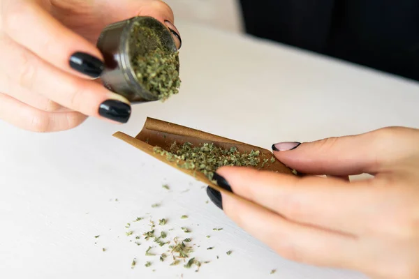 Cannabisgebruik concept. Een vrouw met een marihuana joint op een witte achtergrond. Vrouw die marihuana maakt en rolt. Sluiten van marihuana stomp met molen. — Stockfoto