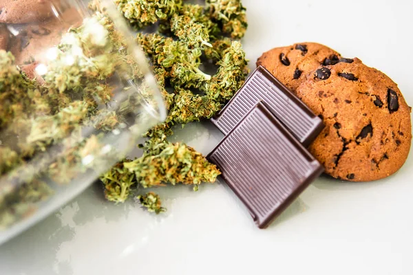 Bolachas com erva de cannabis CBD. Biscoitos com maconha e botões de maconha na mesa. Tratamento de maconha medicinal para uso em alimentos, fundo branco . — Fotografia de Stock