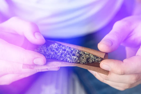 Marihuana GRINDER Cannabiskonsum Konzept. Großaufnahme von Mann, der einen Cannabis-Stumpf auf weißem Hintergrund rollt. Mann bereitet Marihuana vor und rollt es stumpf. — Stockfoto