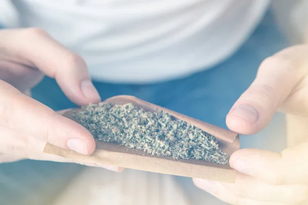 Mann bereitet Marihuana vor und rollt es stumpf. Marihuana GRINDER Cannabiskonsum Konzept. Nahaufnahme eines Mannes, der einen Cannabis-Stumpf auf weißem Hintergrund rollt. — Stockfoto