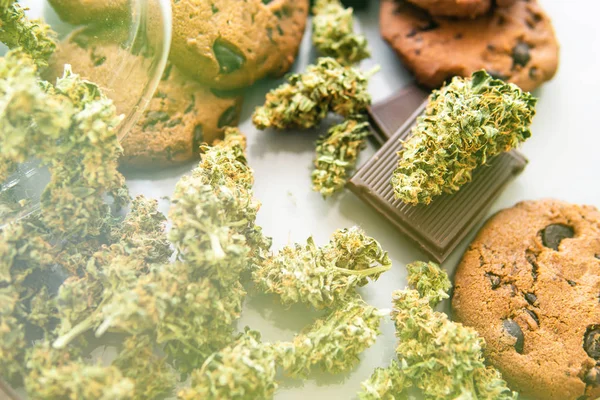 Tratamento de maconha medicinal para uso em alimentos, fundo branco. Bolachas com erva de cannabis CBD. Biscoitos com maconha e botões de maconha na mesa. fugas de luz — Fotografia de Stock