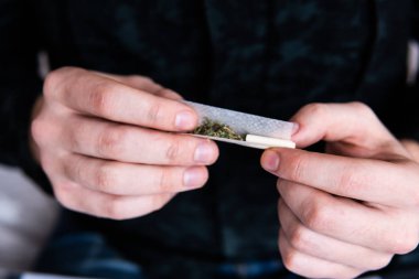 Esrar saran bir adam. Marihuana hazırlayan ve yuvarlayan adam. Uyuşturucu narkotik konsepti. Esrarkeşin çakmakla esrar içtiği yeri kapatın. Kapatın. Uyuşturucu kullanımı.